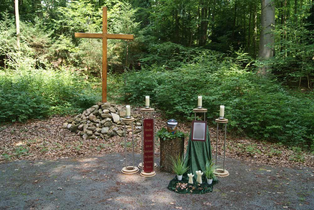 trauerfal Urne im Wald mit Holzkreuz